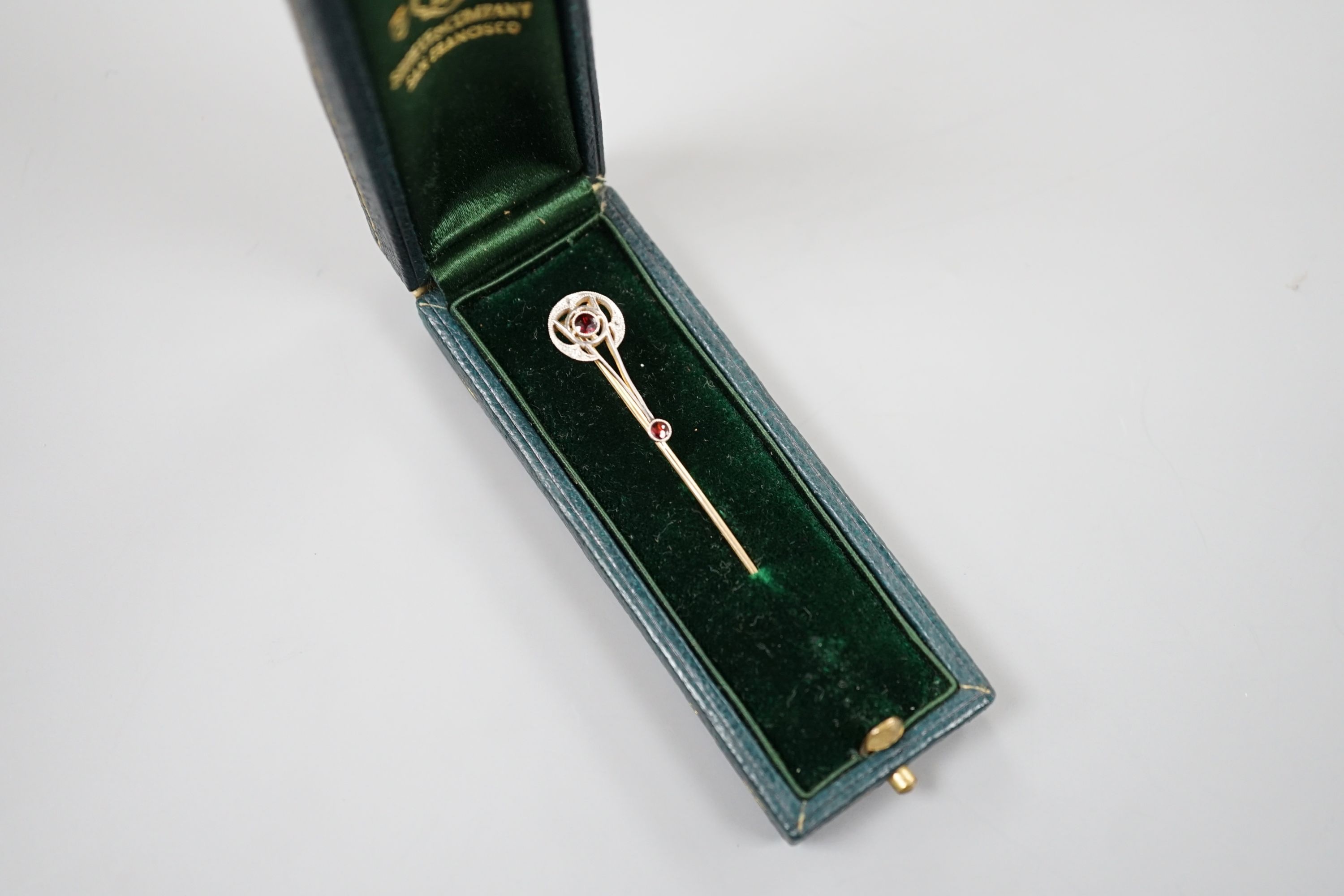 A cased American 14k, garnet and diamond chip set stick pin, by Shreeve & Company, 67mm, gross weight 2.3 grams.